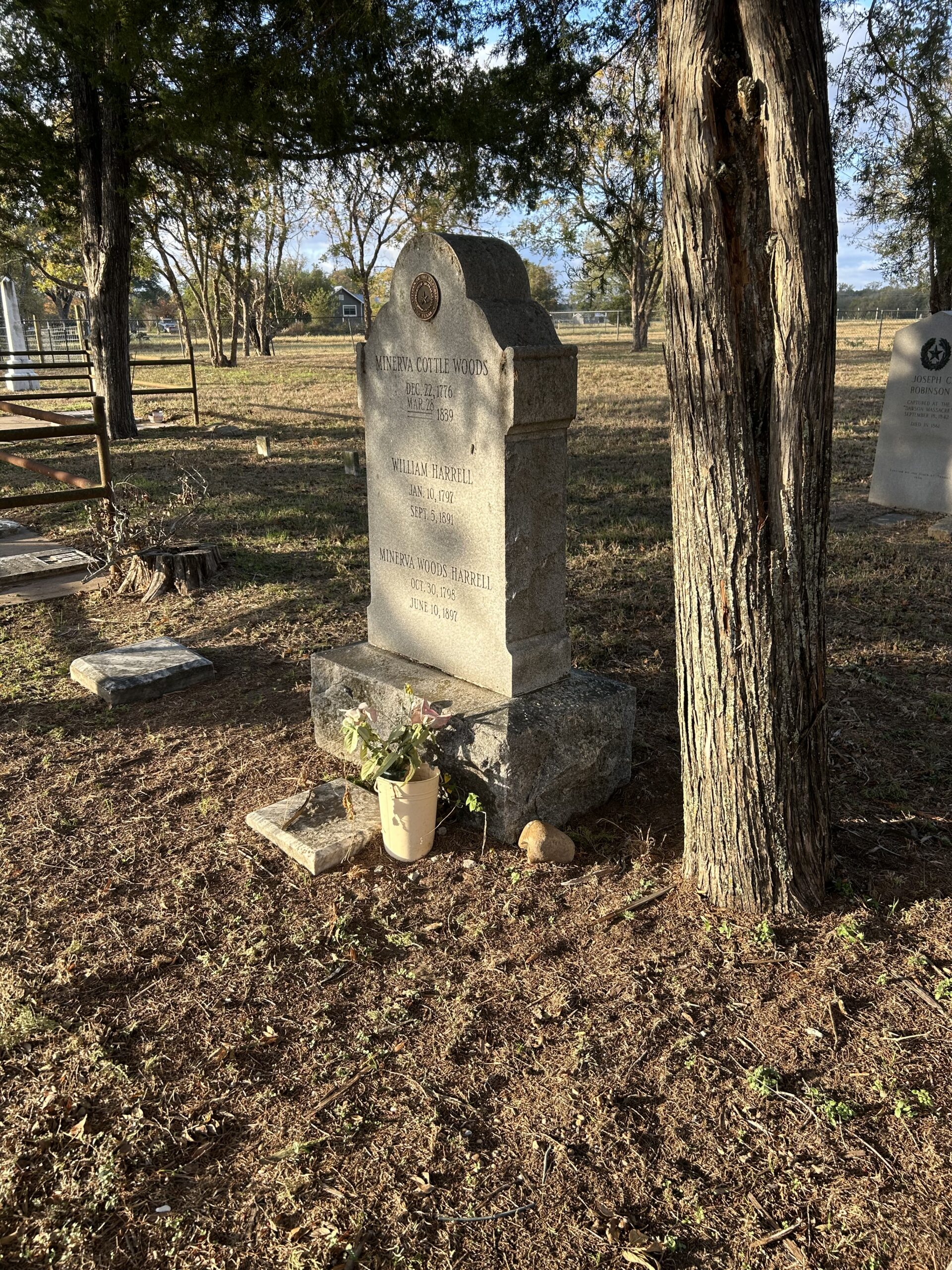 Cemetery monument honoring Henrietta Cottle Woods, William T. Farrell, and Andrew Woods Farrell beneath mature trees