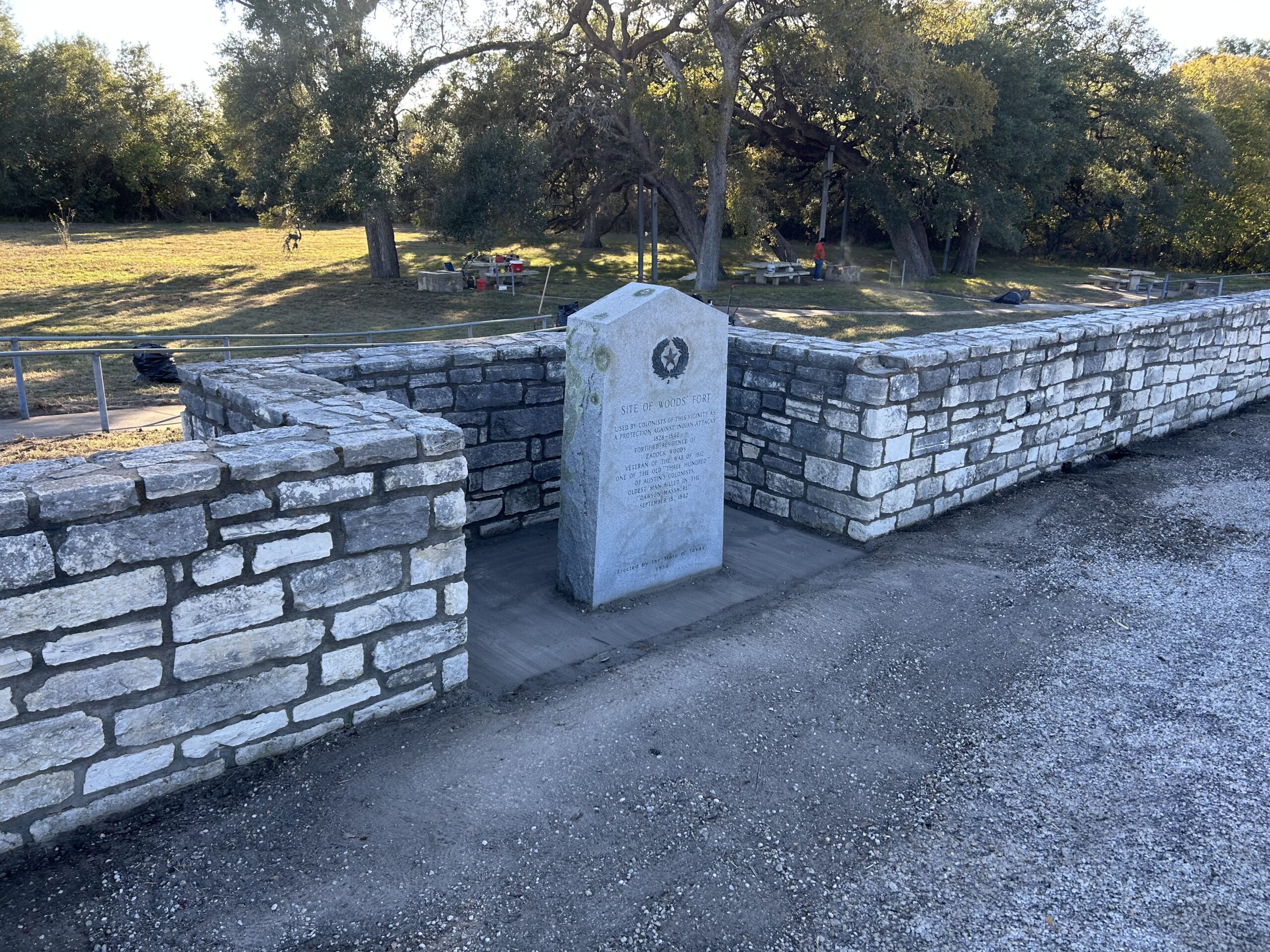Woods Fort historical monument surrounded by a curved stone wall and trees